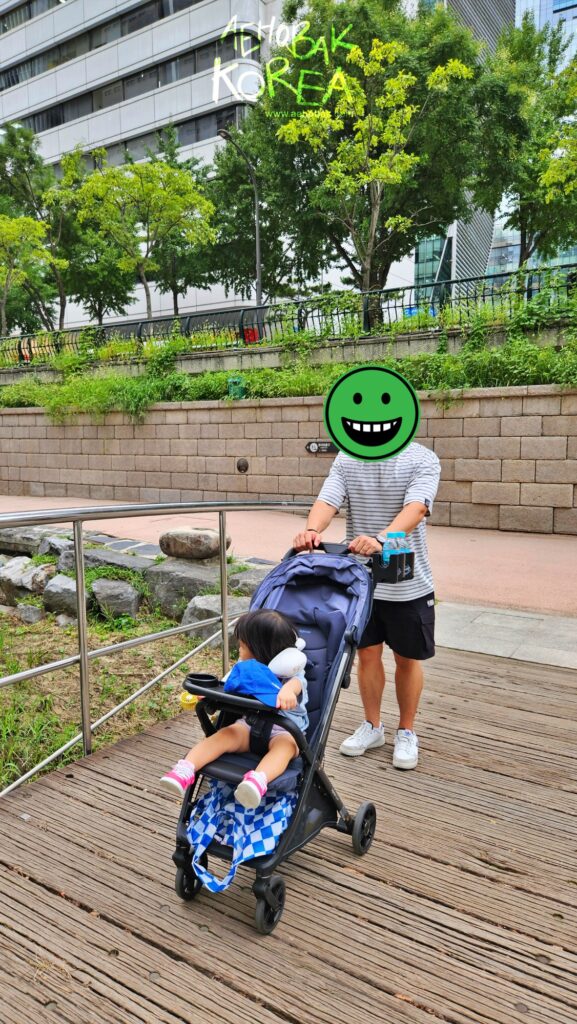 a man with stroller on a kid walking in cheonggyecheon
