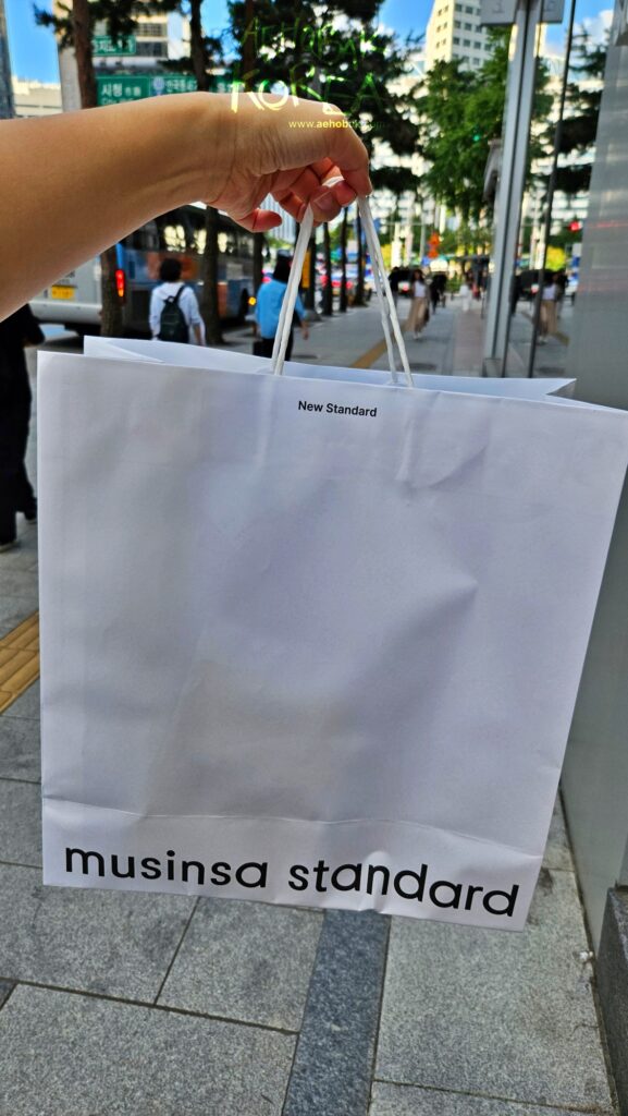 Musinsa Standard shopping bag held outside on a street in Myeongdong, Seoul.