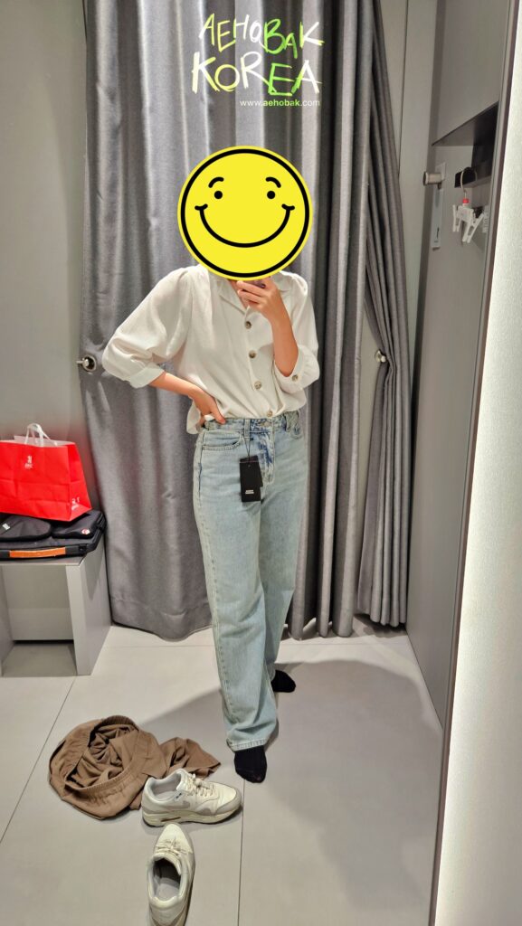 Traveler wearing light blue jeans in the fitting room at Musinsa Standard Myeongdong.